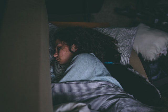 woman sleeping in bed underneath blankets