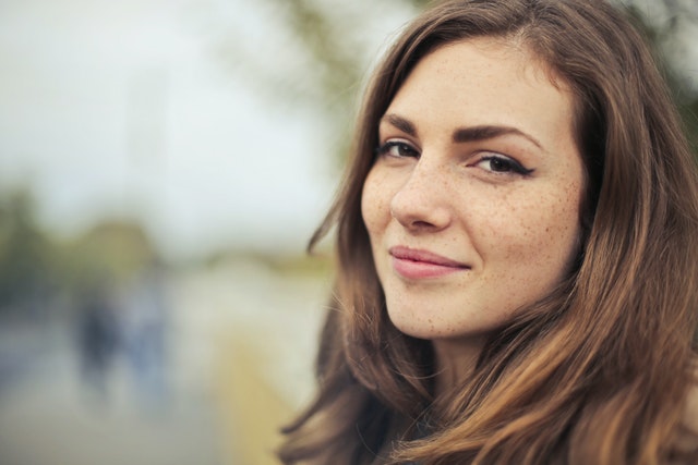 woman smiling at camera leaning against a wall