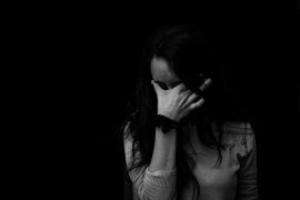 A woman with her head in her hand, experiencing difficulty.